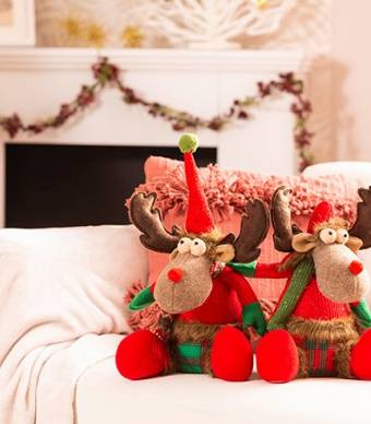 Duas renas natalícias sentadas em cima de um sofá a decorar